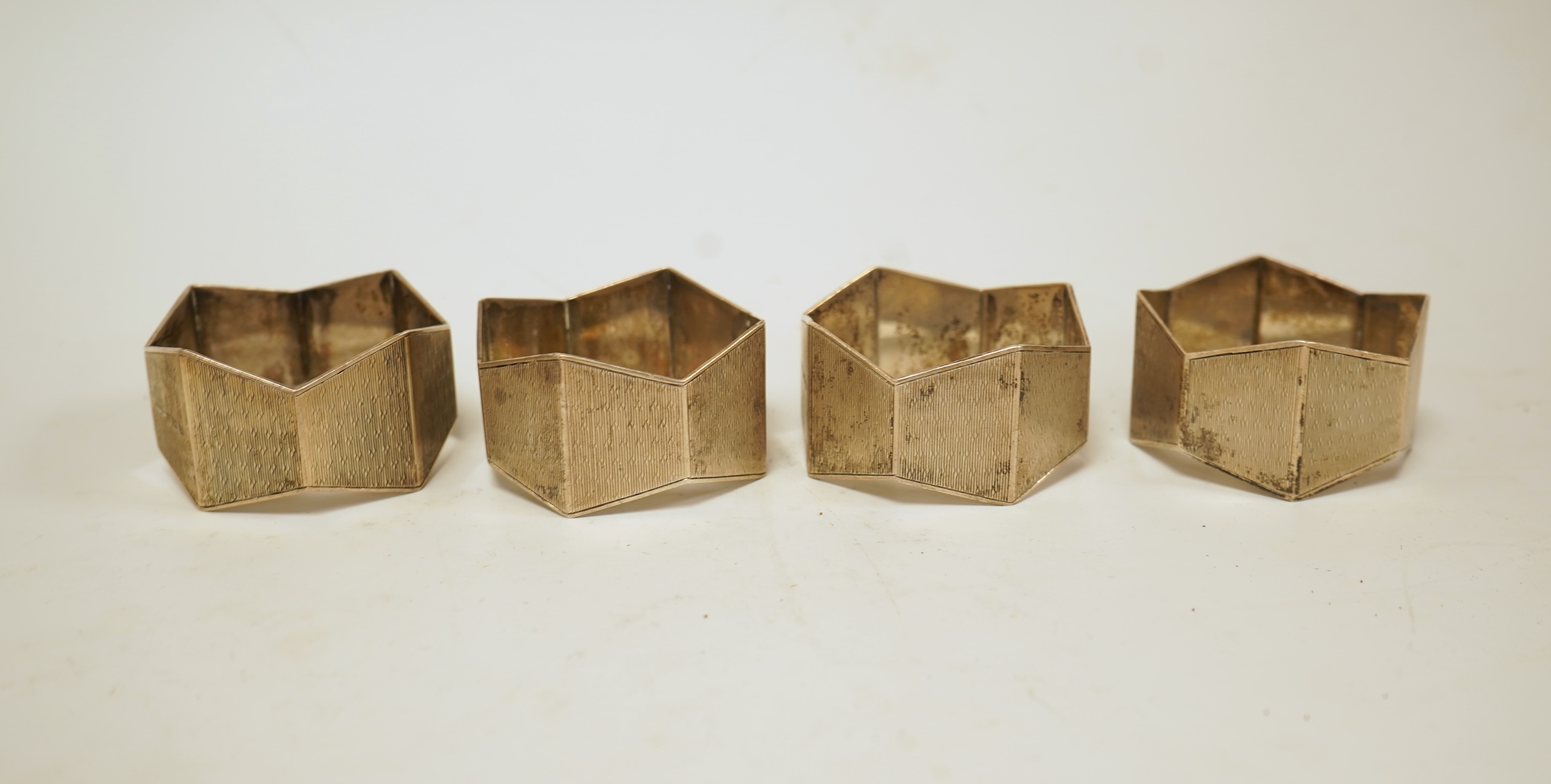A small silver mounted capstan inkwell, a set of four George V engine turned silver napkin rings and a silver handled magnifying glass.
